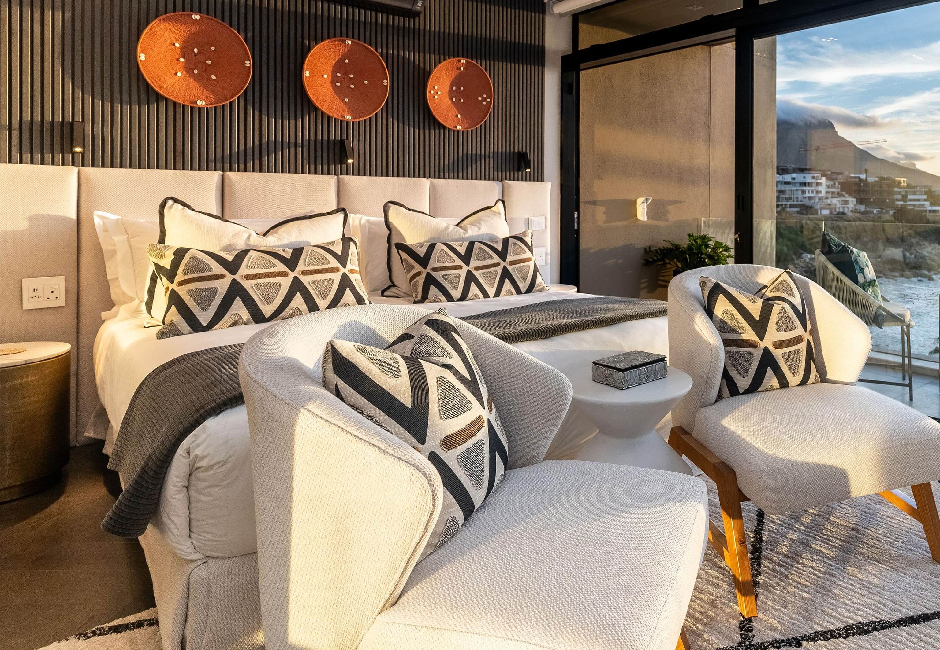 Bedroom with chevron cushions, copper wall discs and a window view of the mountain and sea